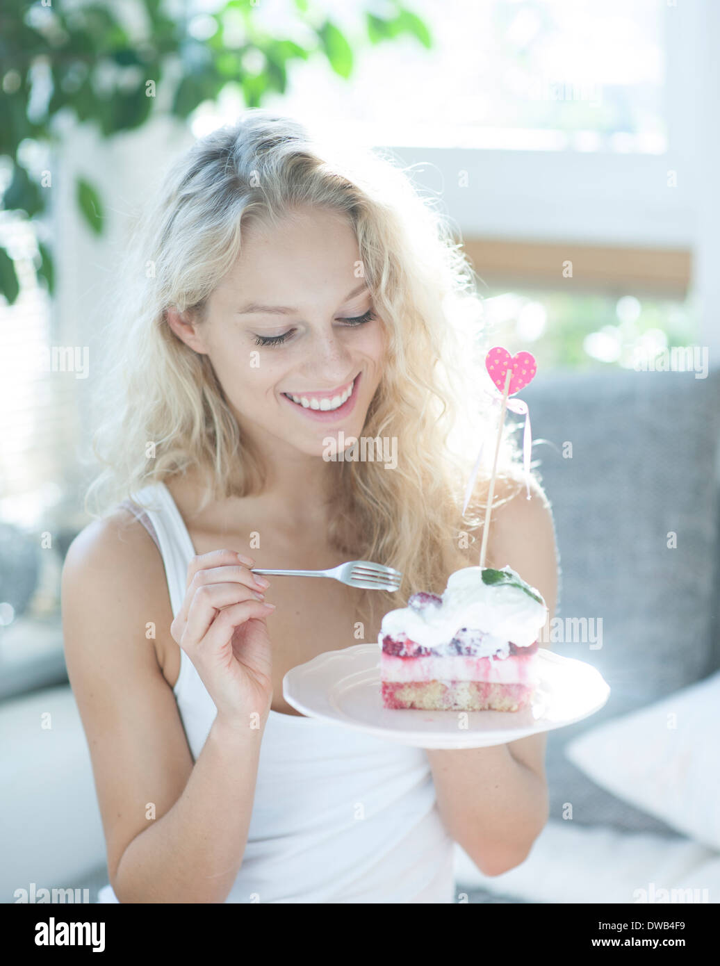 Schöne Frau mit Himbeer Kuchen mit Gabel im Haus Stockfoto