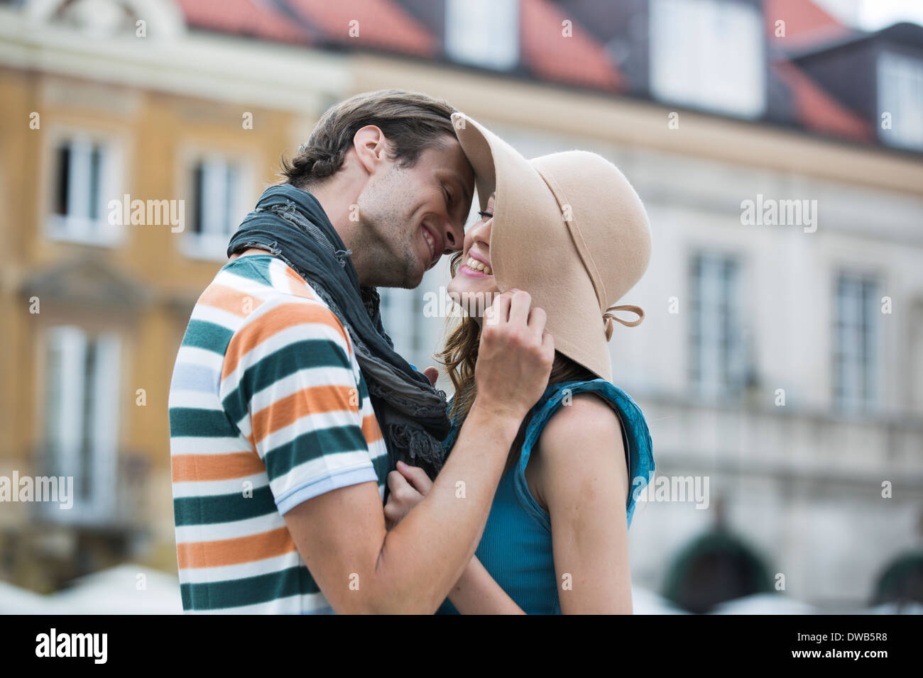 Romantischer junger Mann küsst Frau gegen Gebäude Stockfoto