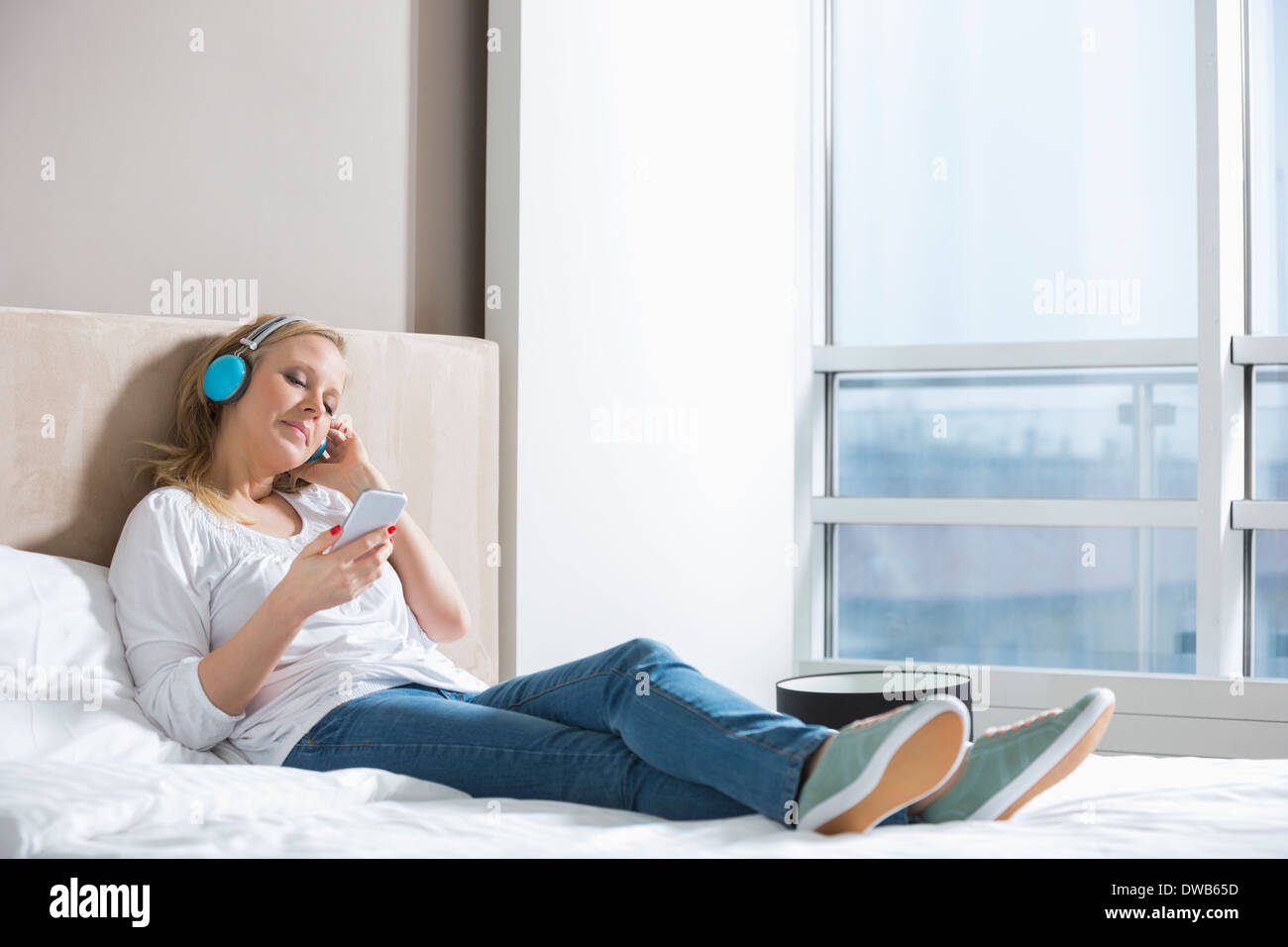 Volle Länge des entspannten Frau Musik hören im Schlafzimmer Stockfoto