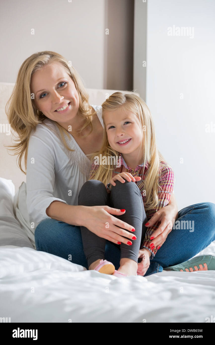 Porträt der glückliche Mutter und Tochter sitzen am Bett zu Hause Stockfoto