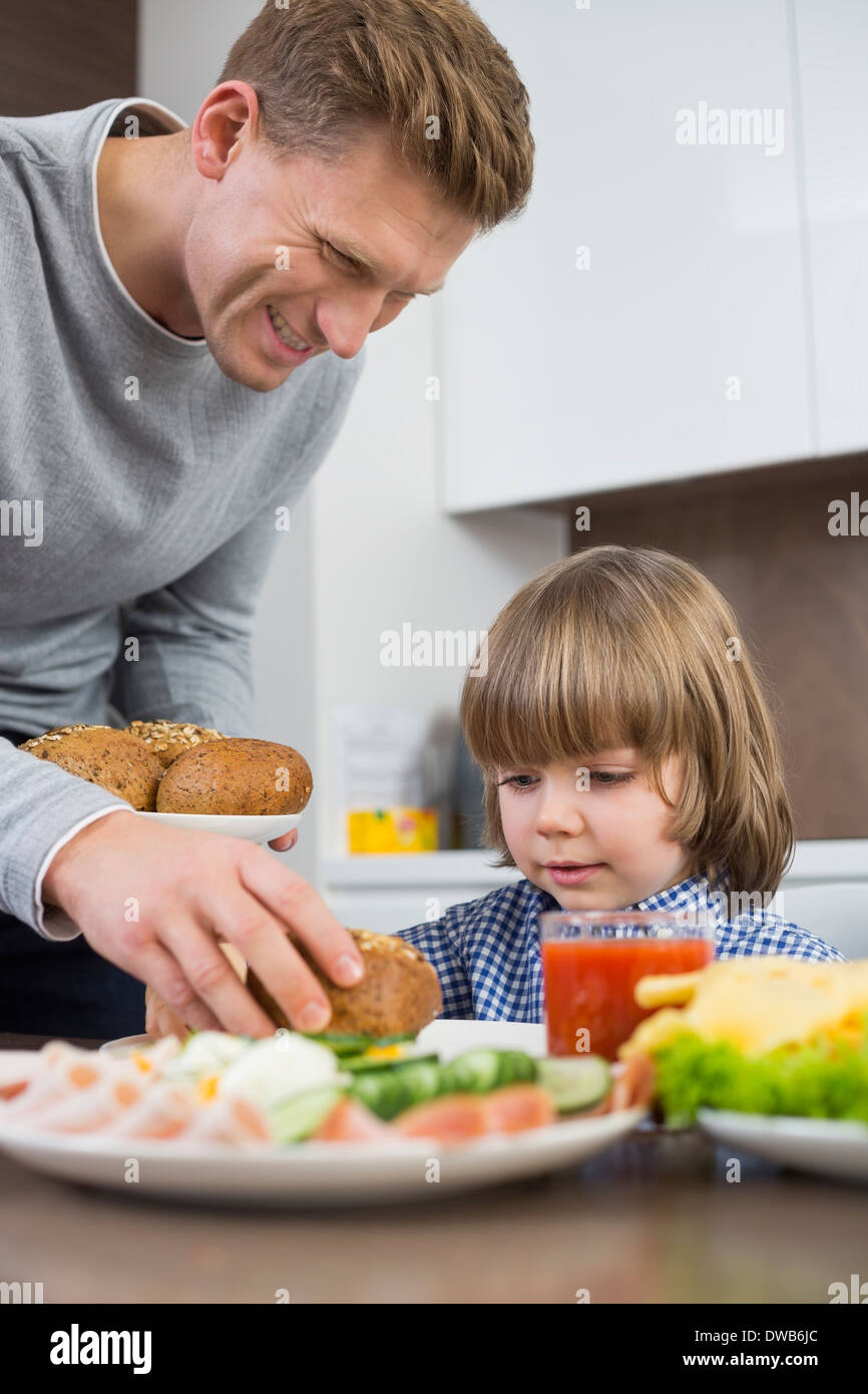 Glücklicher Vater servieren Mahlzeit Sohn am Tisch in der Küche Stockfoto