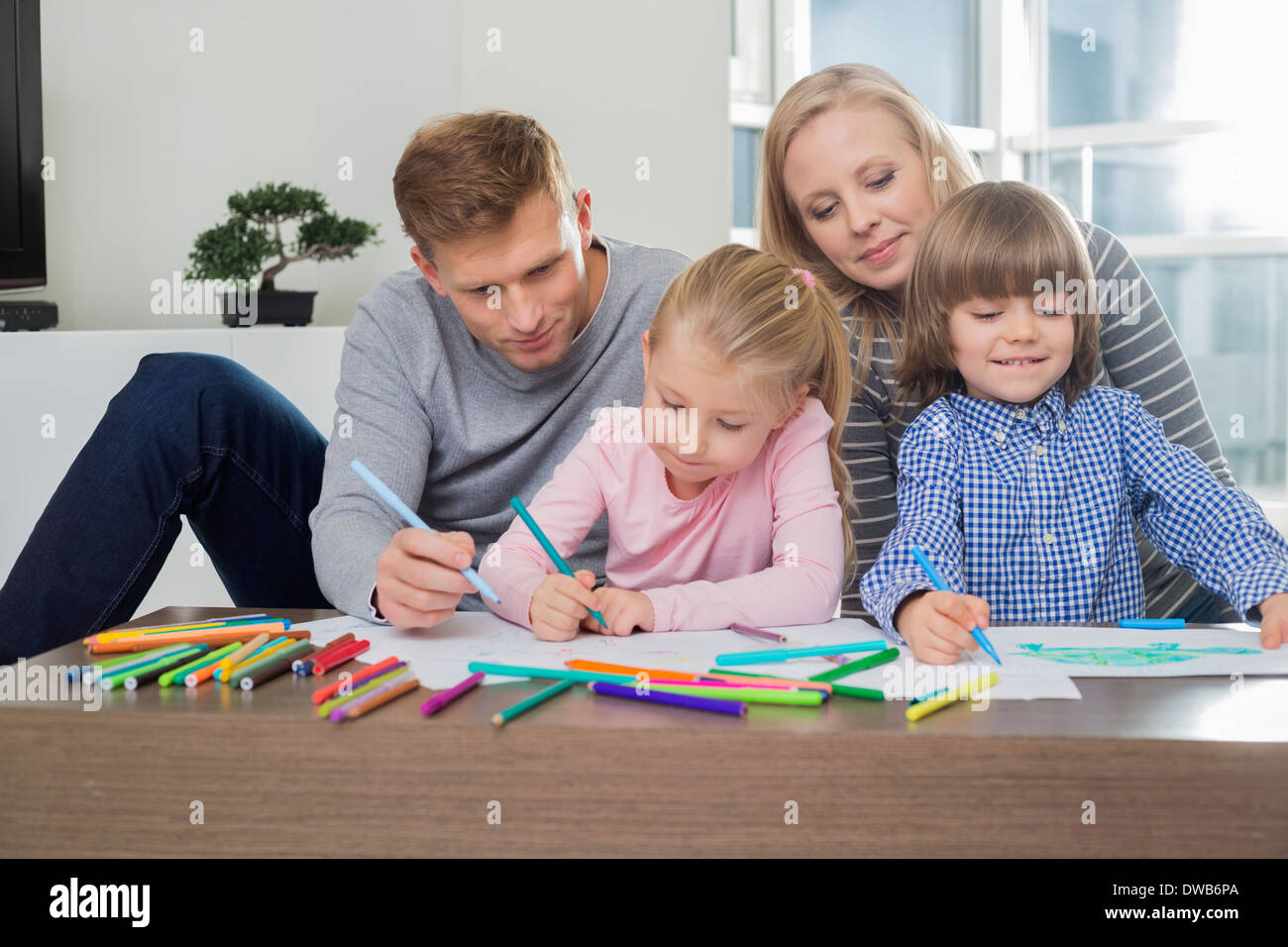Mitte Erwachsenen Eltern mit Kindern zusammen zu Hause zeichnen Stockfoto