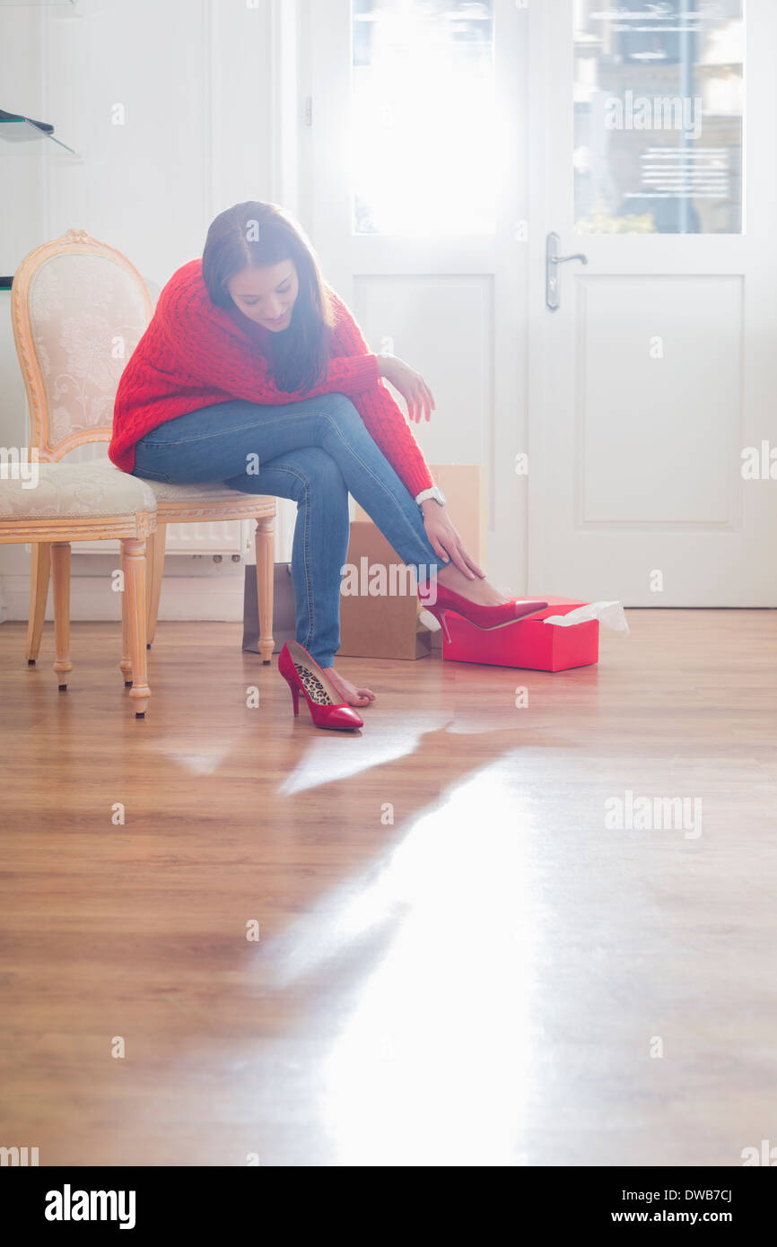 Gesamte Länge der jungen Frau, die Schuhe im Laden anprobieren Stockfoto