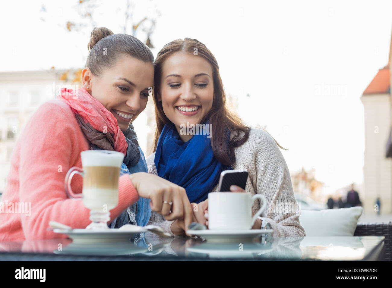 Glücklich Freundinnen mit Handy im Straßencafé Stockfoto