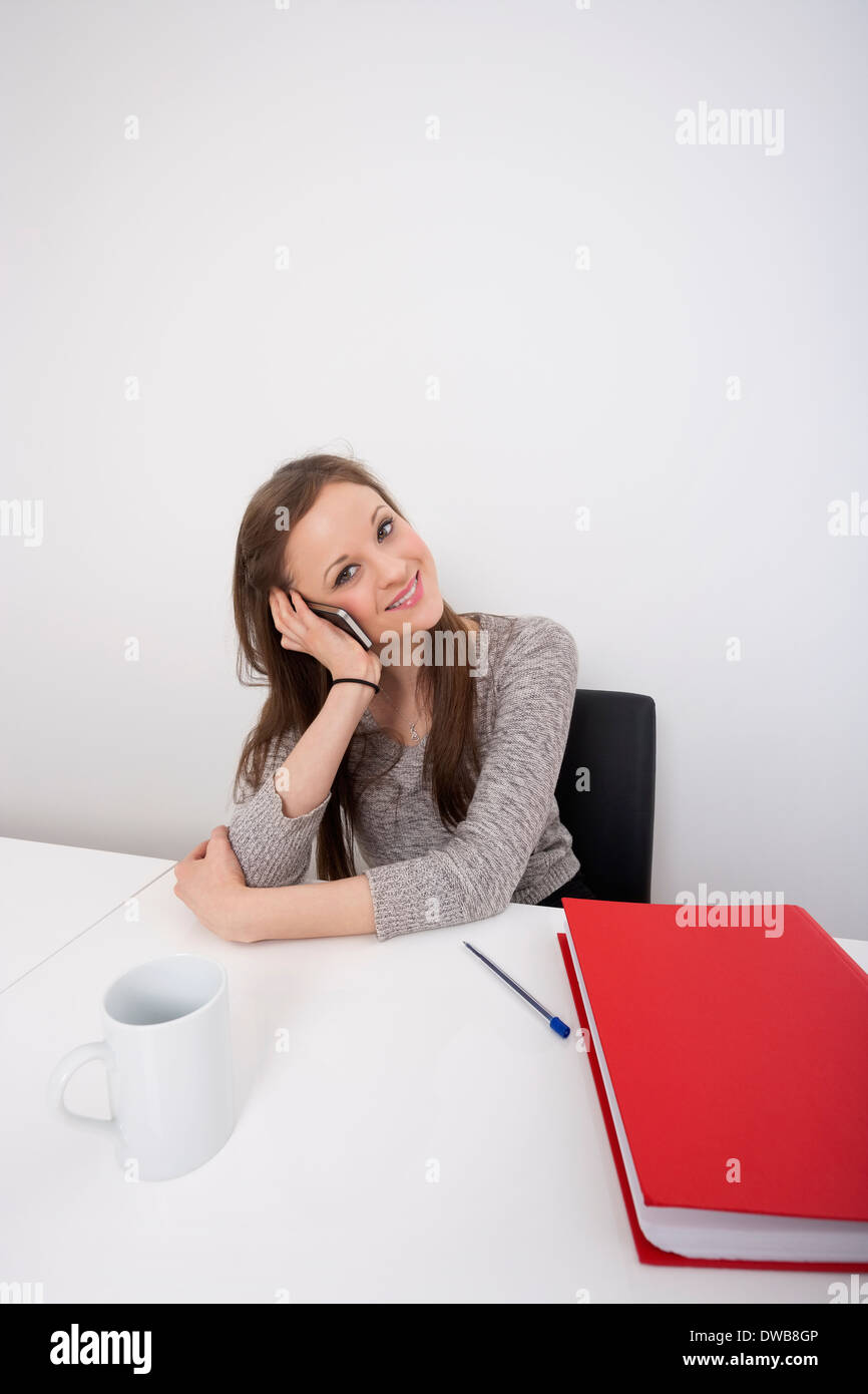 Porträt der schönen Geschäftsfrau mit Handy am Schreibtisch Stockfoto