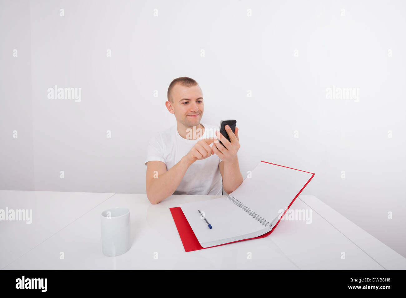 Lächelnd Geschäftsmann SMS auf Handy auf Schreibtisch Stockfoto