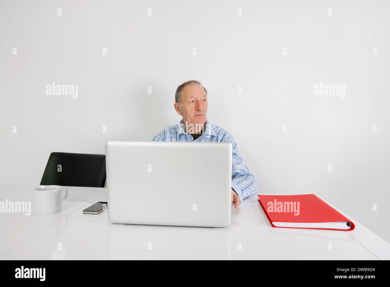 Nachdenklich senior Geschäftsmann mit Laptop am Schreibtisch Stockfoto