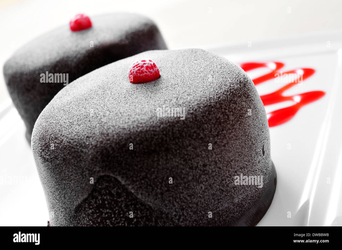 Nahaufnahme von einem gefrorenen Schokoladendessert in einem Teller mit Erdbeer-Sirup Stockfoto