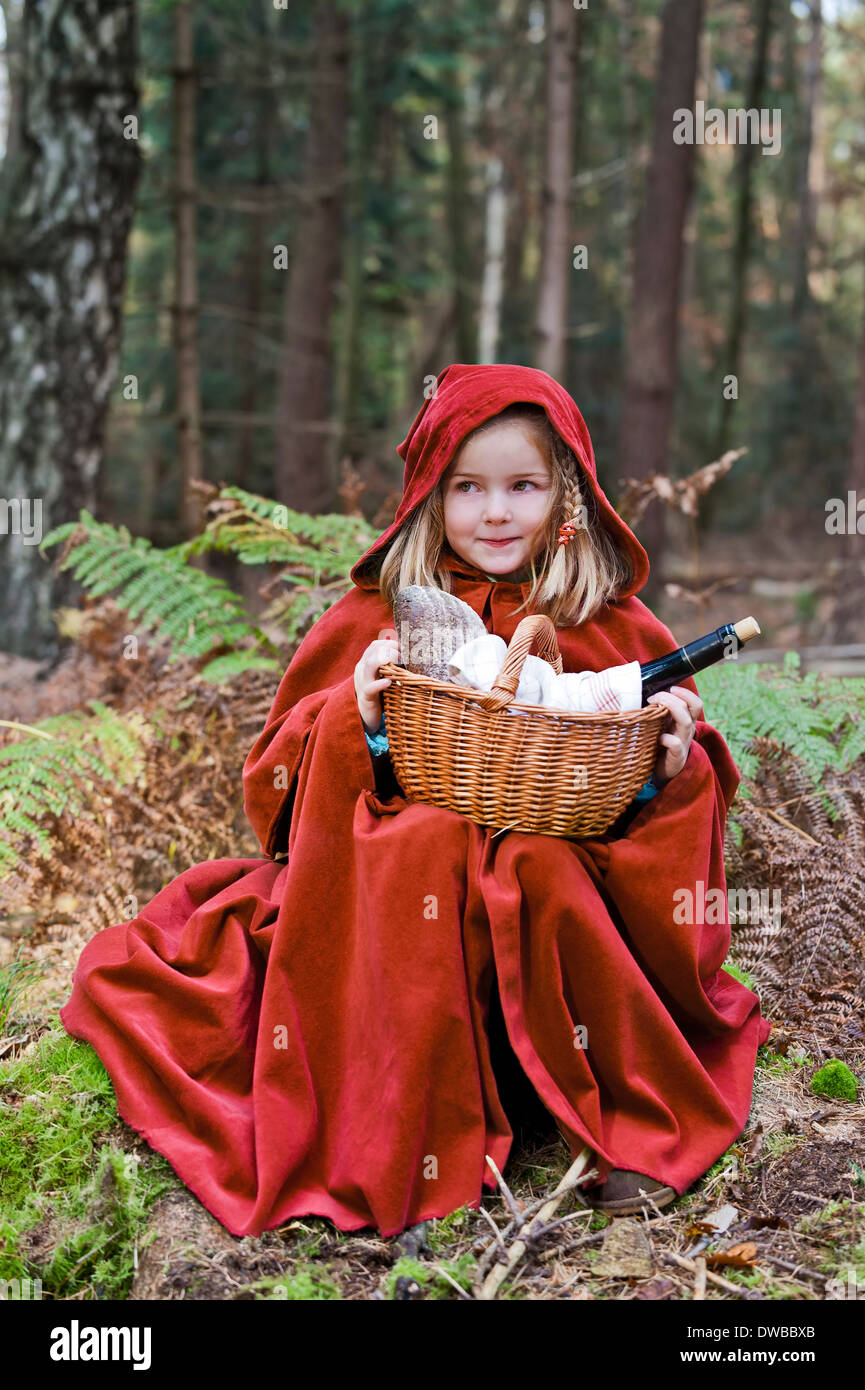 Kleine Mädchen Maskerade als Rotkäppchen im Wald sitzen Stockfoto