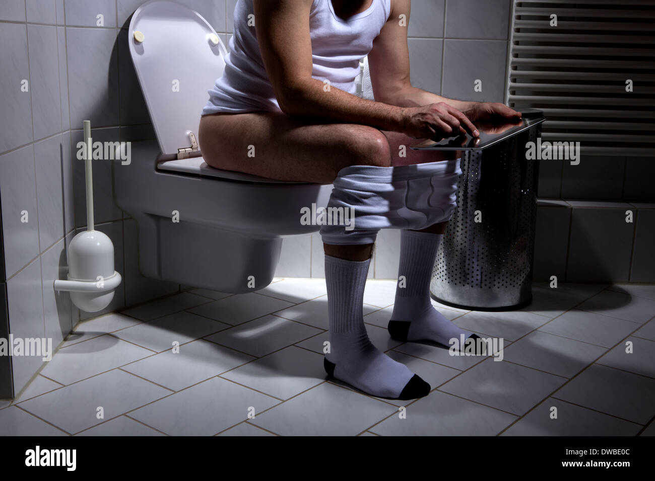 Deutschland, Mann sitzt auf Toilette, mit digital-Tablette Stockfotografie  - Alamy