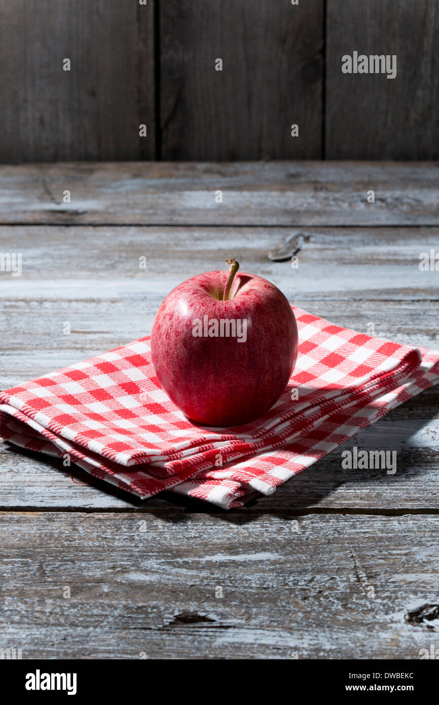 Roter Apfel auf Stoffserviette und Holztisch Stockfoto