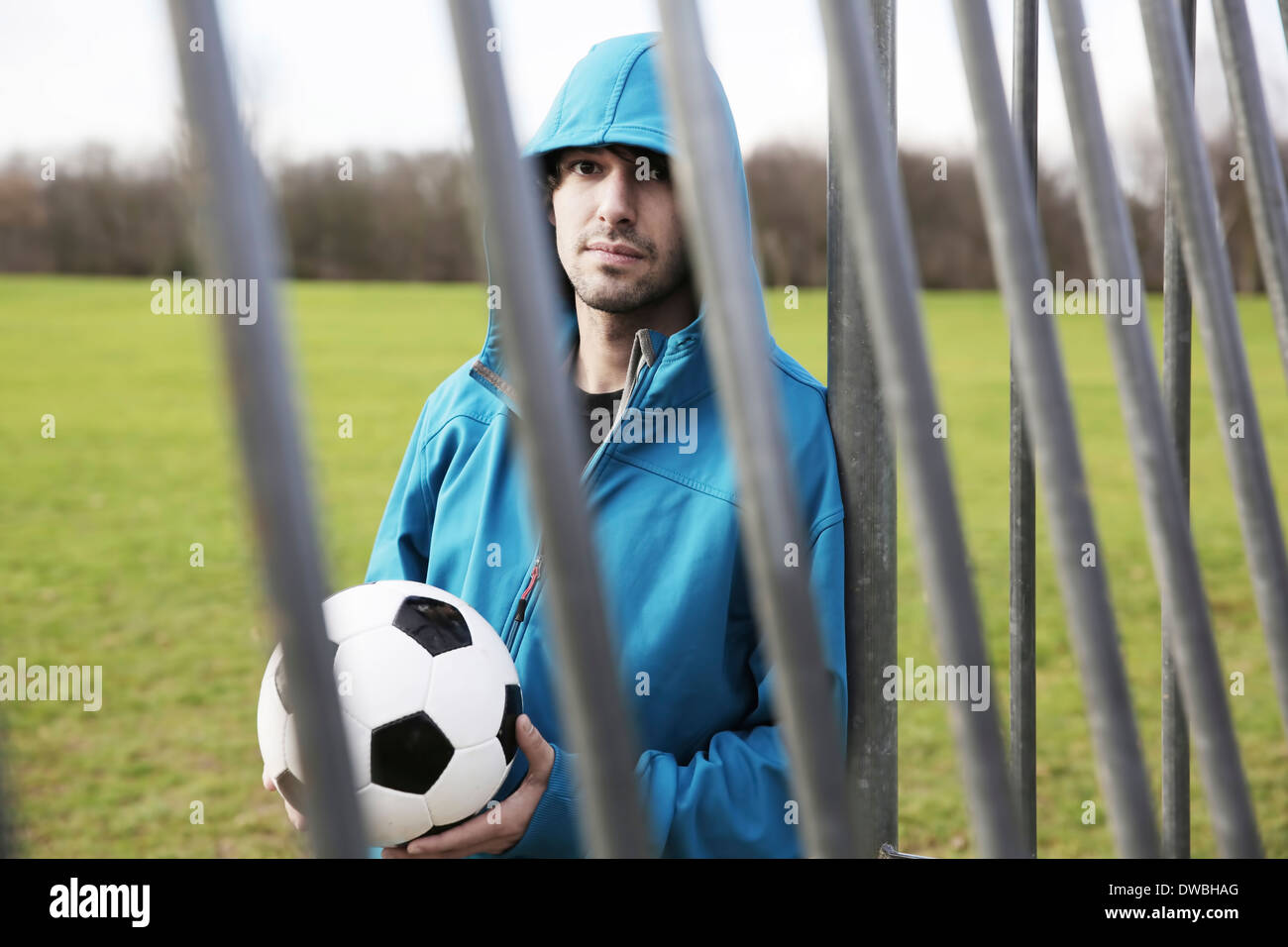 Junger Mann mit Fußball an Torpfosten gelehnt Stockfoto