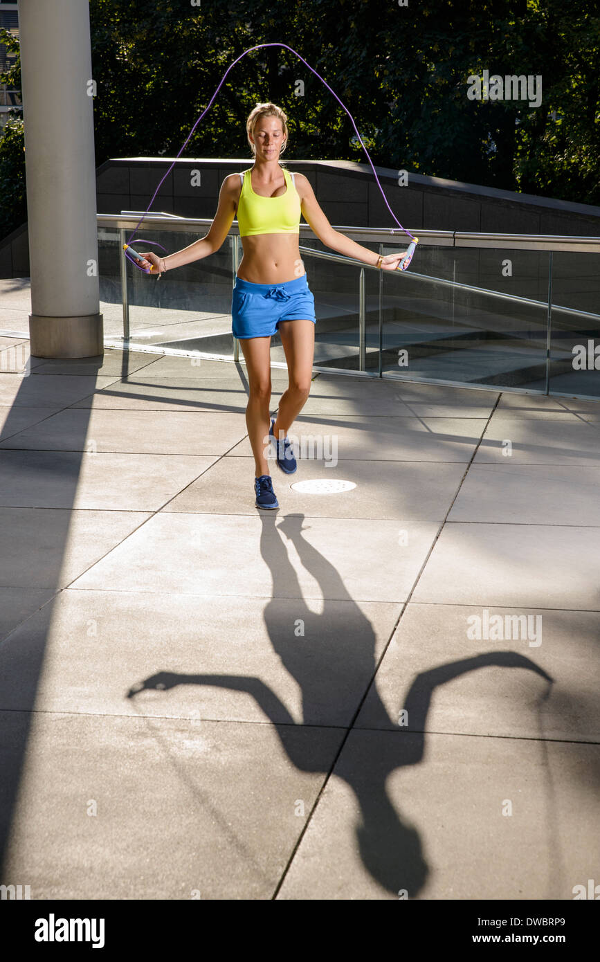 Junge Sportlerin im städtischen Sonnenlicht überspringen Stockfoto