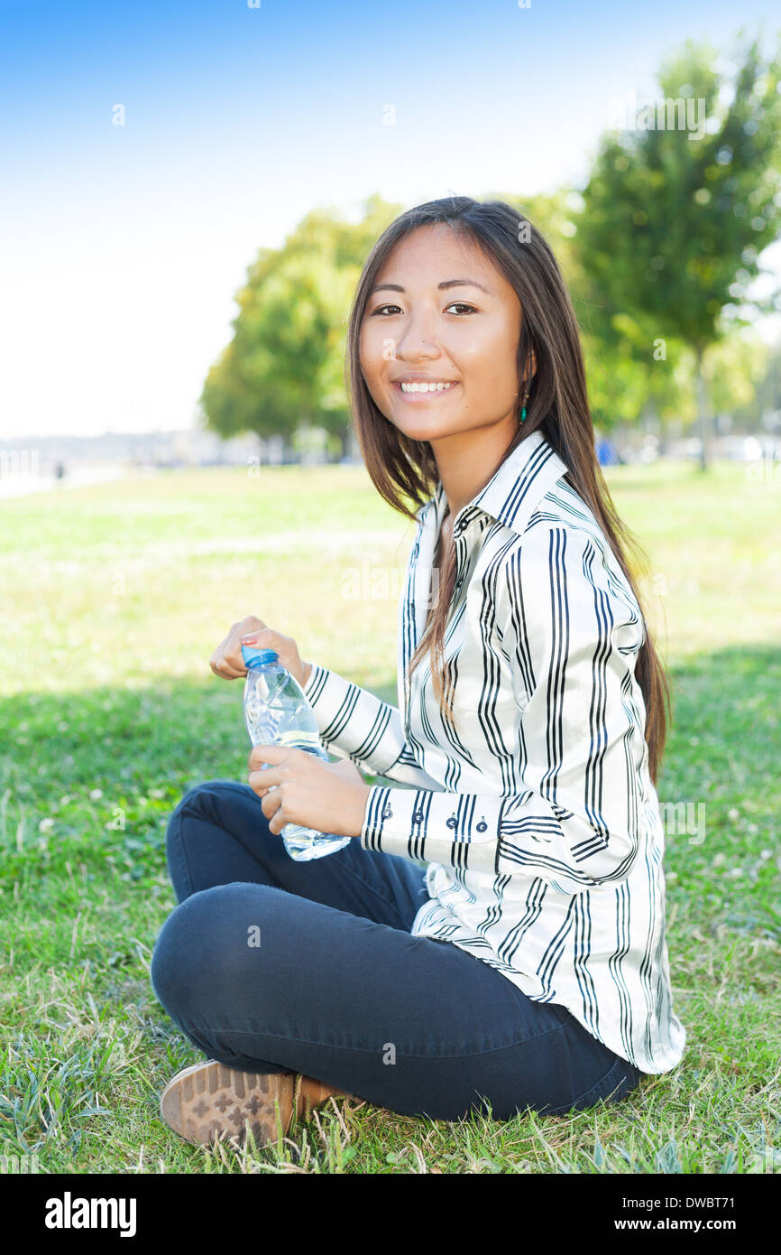 Porträt einer schönen Asiatin in einem Park mit einer Flasche Wasser Stockfoto