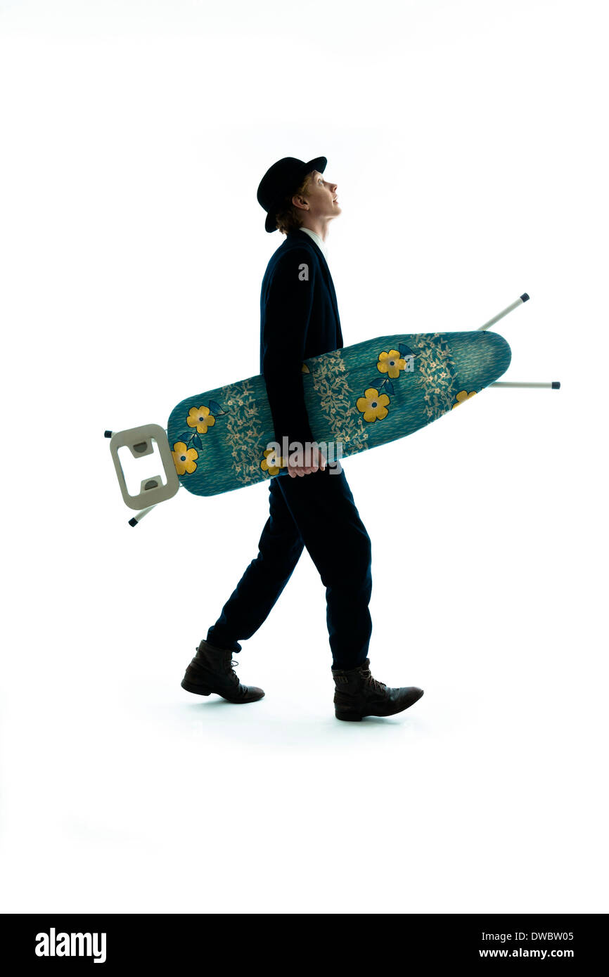 Junger Mann mit Melone unterwegs mit Bügeleisen /-Brett, Studio gedreht Stockfoto
