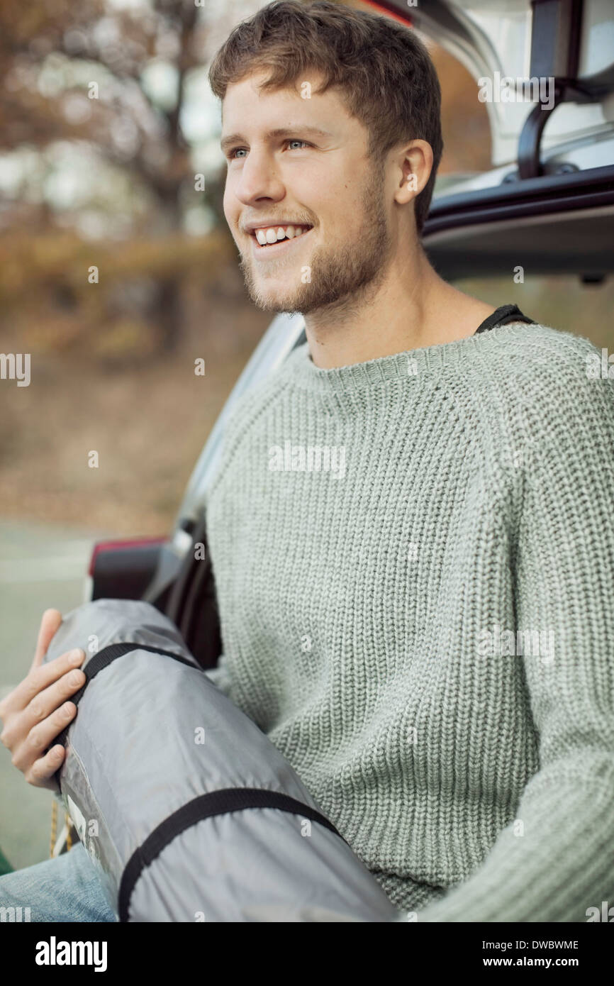 Junger Mann mit Schlafsack im Kofferraum eines Autos Stockfoto