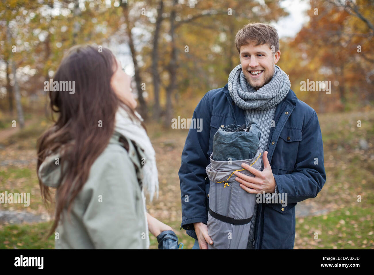 Glücklicher Mann im Winterjacke und Schal Blick auf Frau während camping Stockfoto