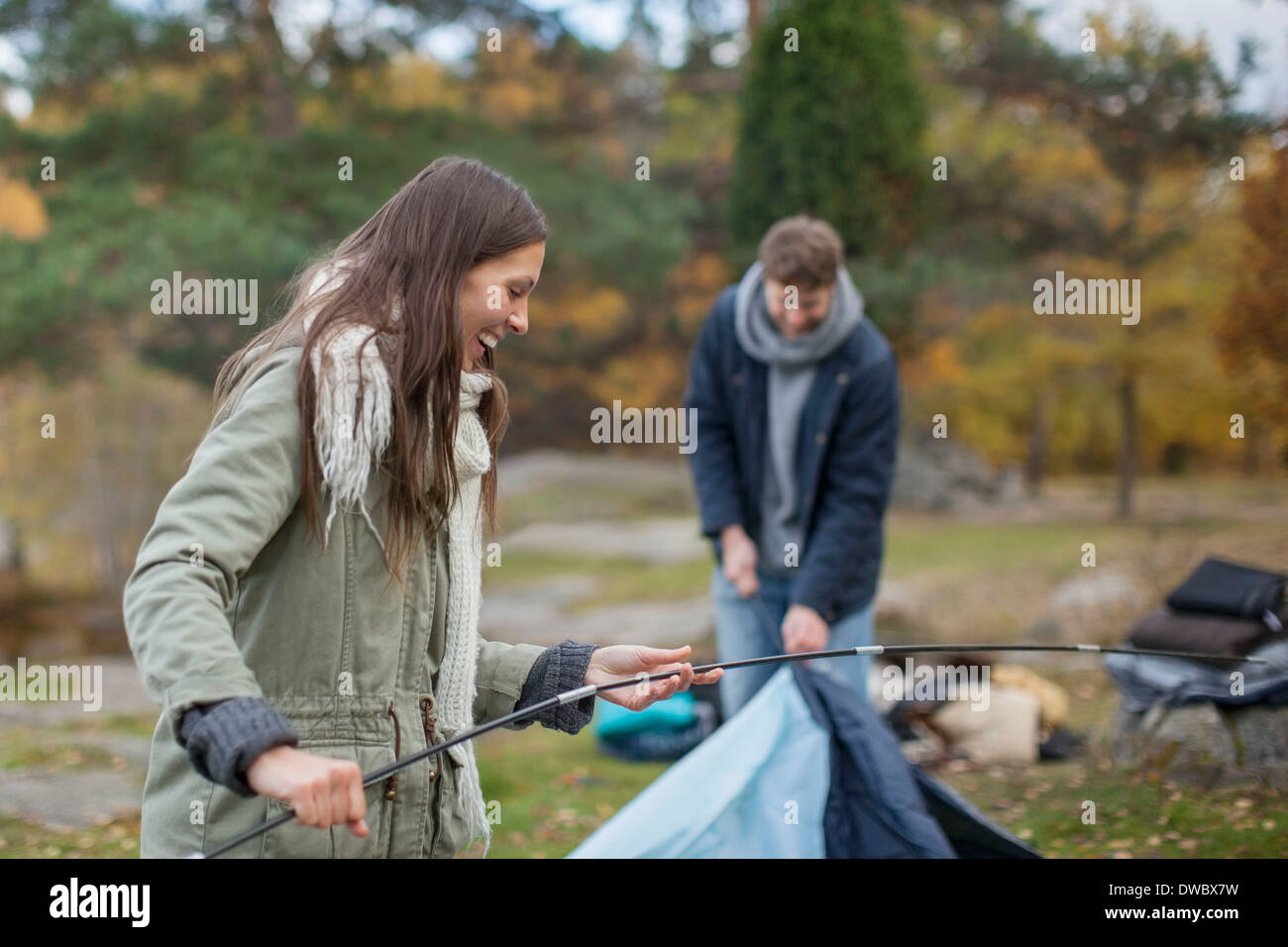 Junge Frau hält des Zeltes Stock mit Mann im Wald Stockfoto