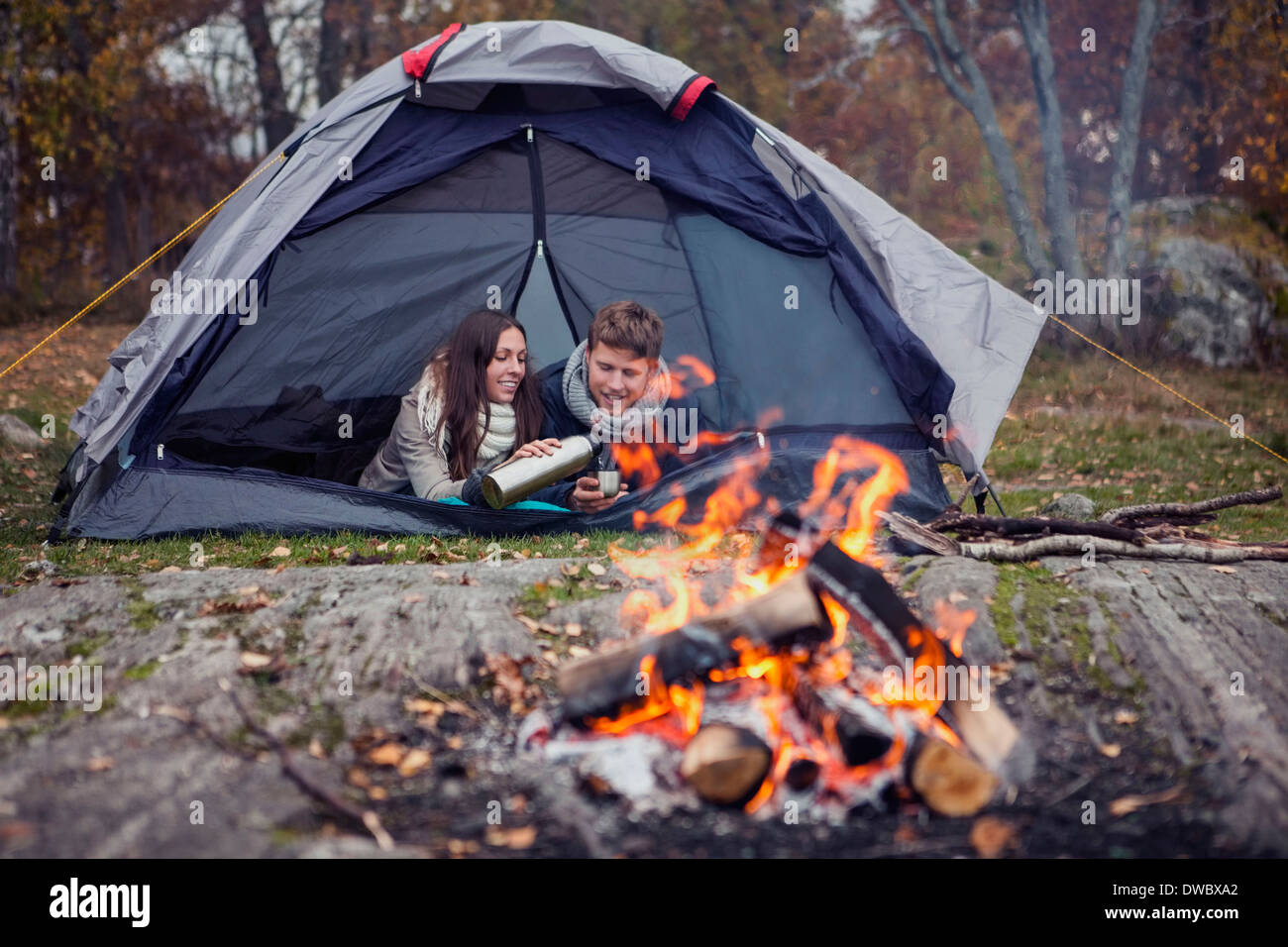 Frau, gießen Kaffee für Mann liegend im Zelt im Wald Stockfoto