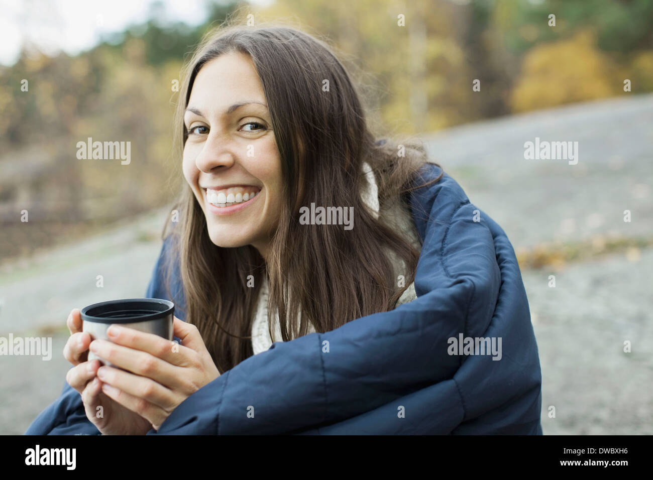 Porträt der glückliche Frau in halten Kaffeetasse beim camping Decke gehüllt Stockfoto