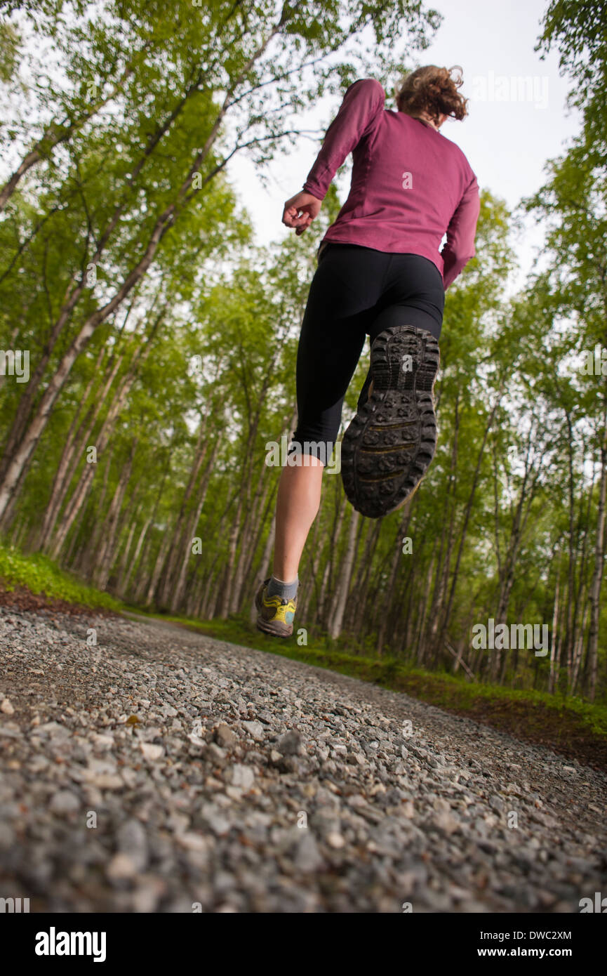 Frau auf einem Schotterweg durch den Wald laufen Stockfoto