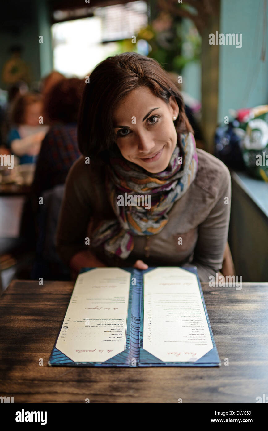 Junge attraktive Frau im Menü in einem Café auf der Suche Stockfoto