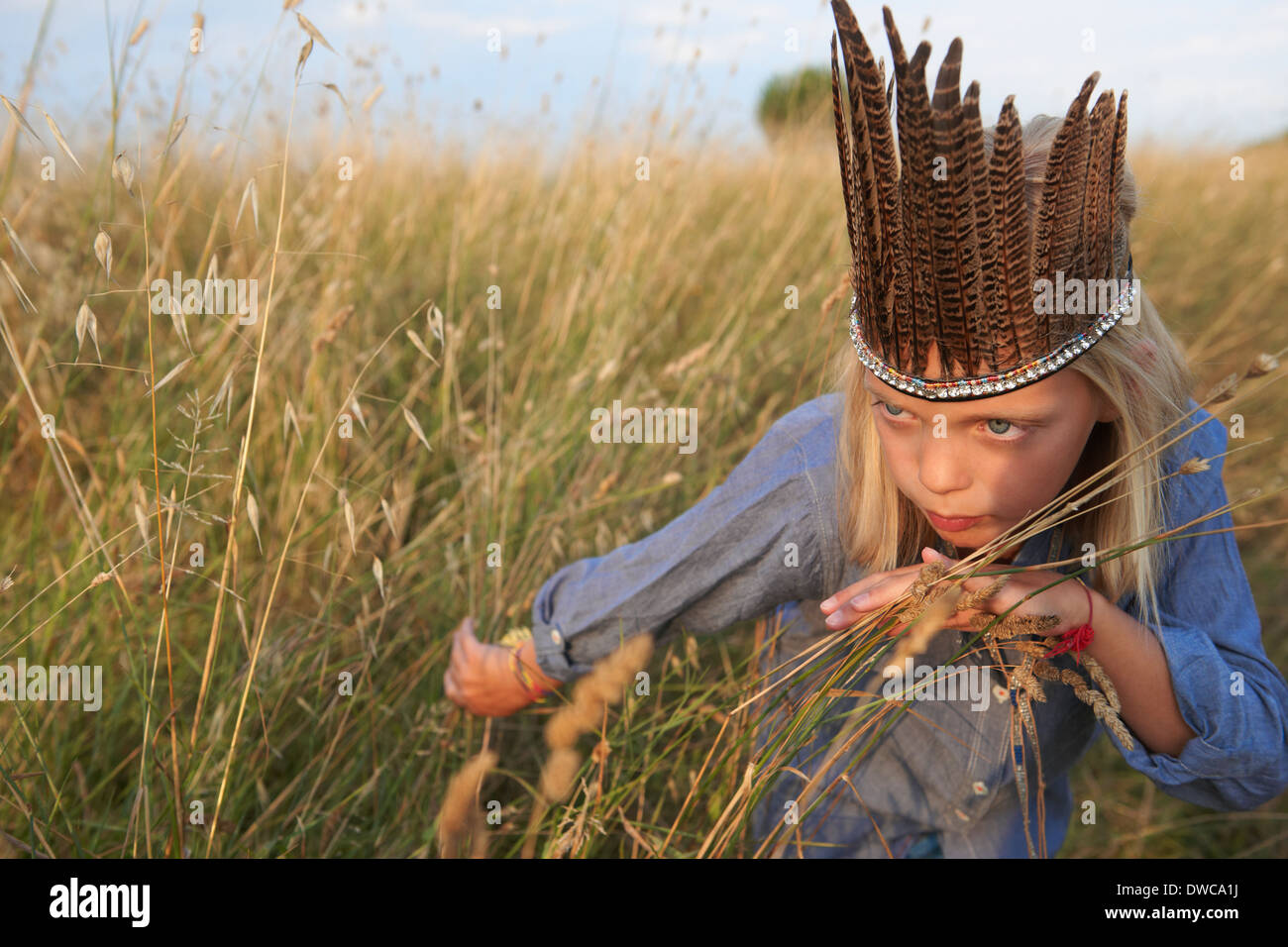 Mädchen versteckt sich in lange Grashalme verkleidet als Native american Stockfoto