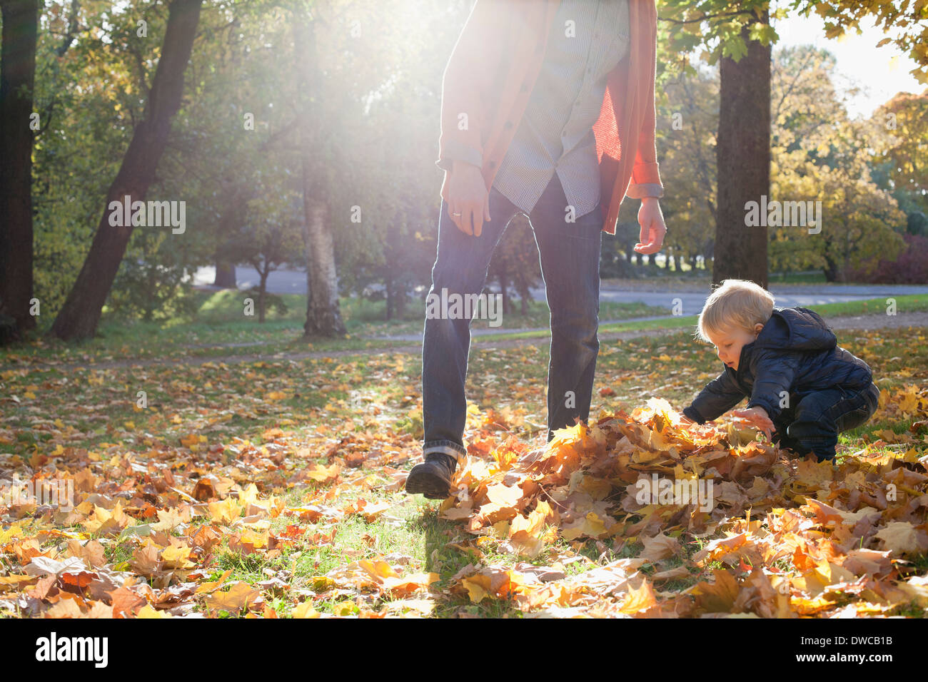 Vater und Sohn spielen mit Herbstlaub Stockfoto