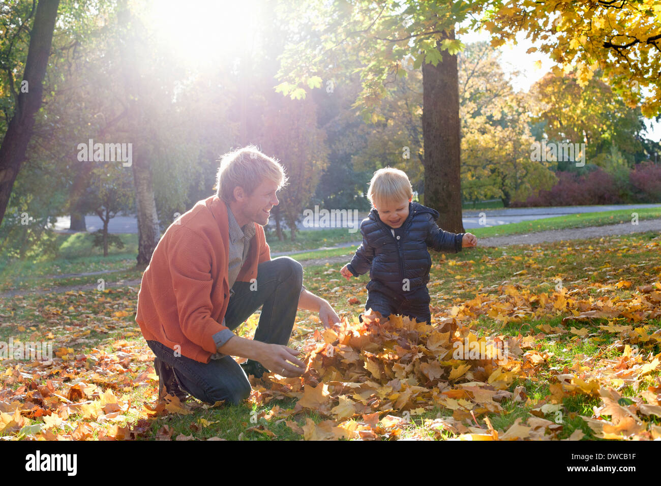 Vater und Sohn spielen mit Herbstlaub Stockfoto