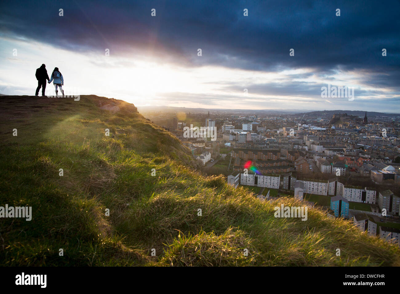 Ein junges Paar an den Händen vor dem Blick auf die Stadt Edinburgh aus Salisbury Crags halten Stockfoto