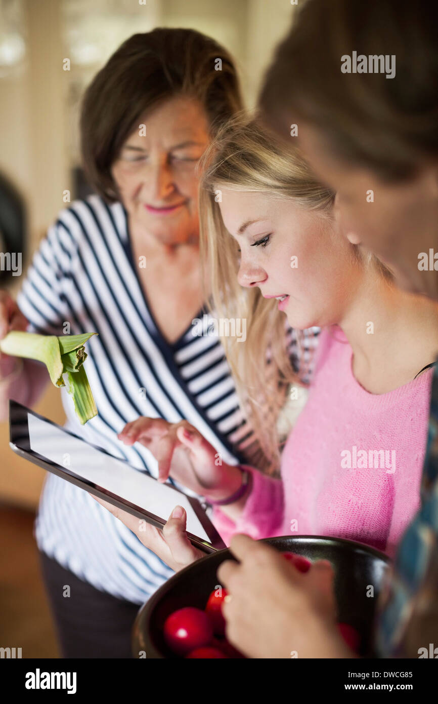 Drei Generationen Frauen Auschecken Rezept auf digital-Tablette in Küche Stockfoto