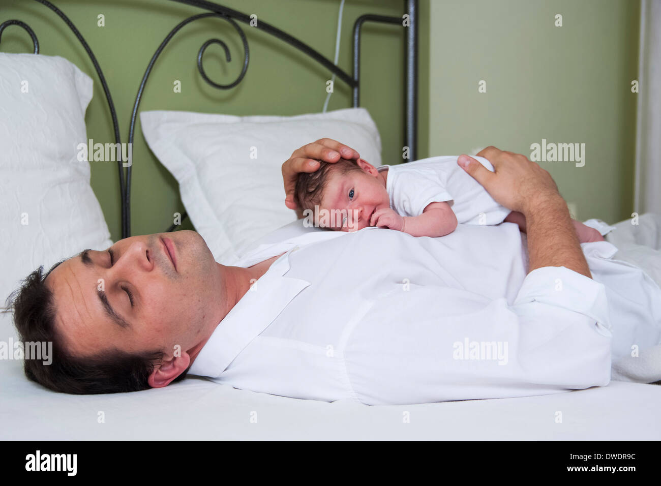 Vater mit Neugeborenen Tochter am Bett liegen Stockfoto