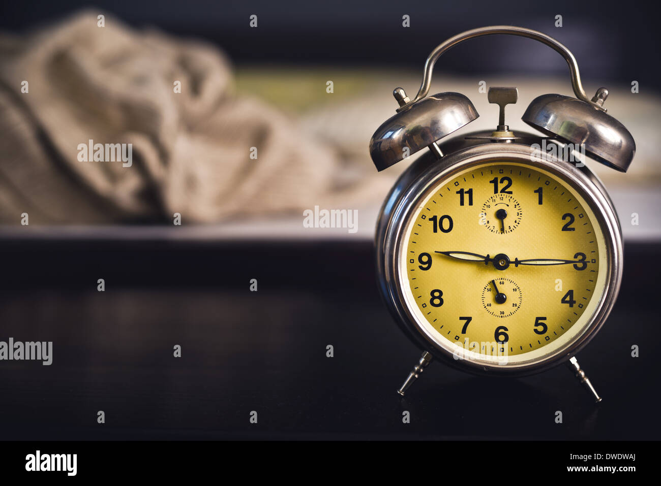 Vintage Wecker im Schlafzimmer auf einem Nachttisch neben dem Bett. Stockfoto