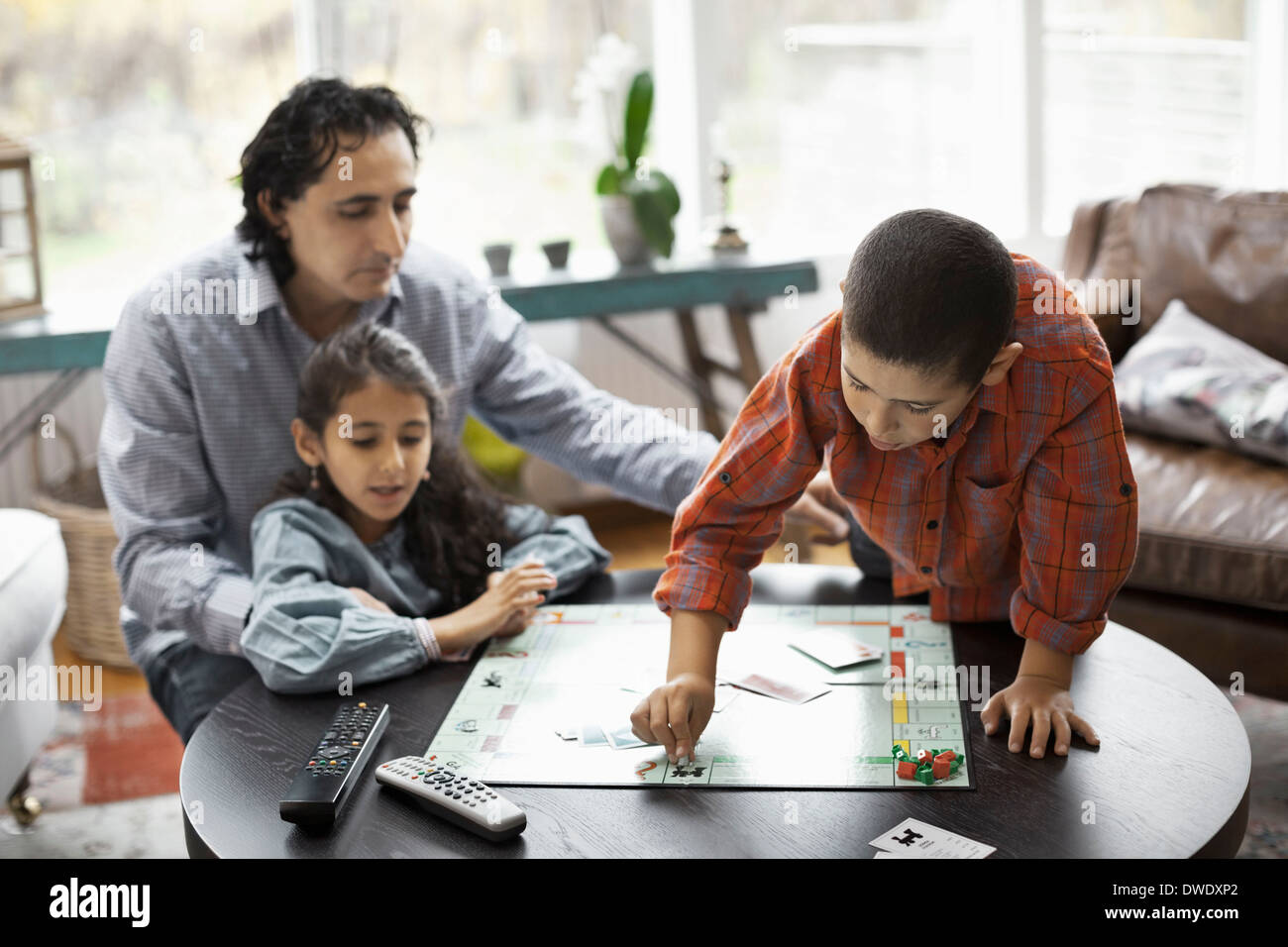 Vater und Kinder spielen Monopoly-Spiel im Wohnzimmer Stockfoto