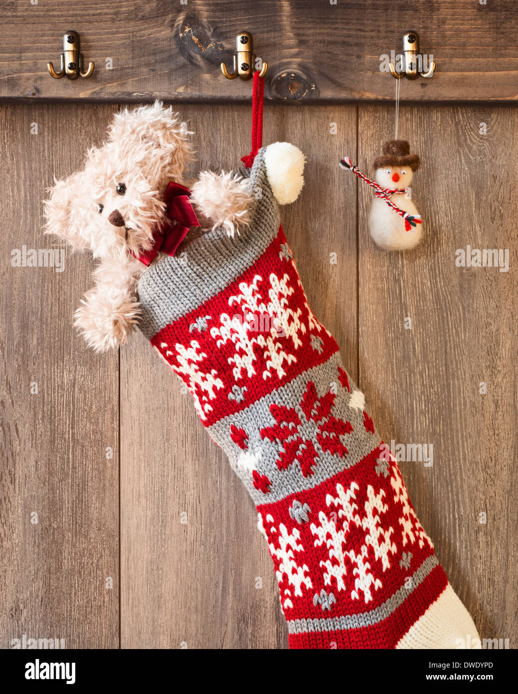 Teddybär in gestrickter Weihnachtsstrumpf mit hängende Dekoration Schneemann Stockfoto