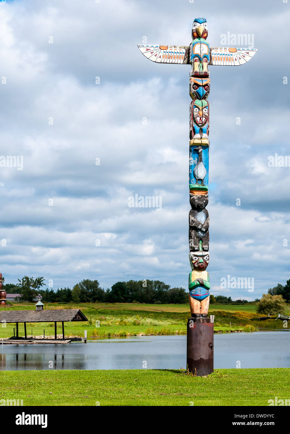 Totempfahl stand neben einem See mit einem bewölkten Himmel. Stockfoto