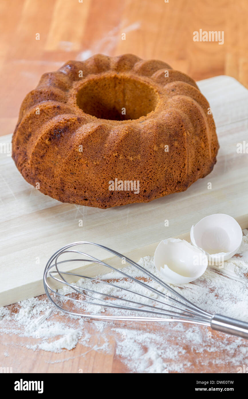 Hausgemachte Kuchen auf Holzbrett mit Eierschalen und Peitsche Stockfoto