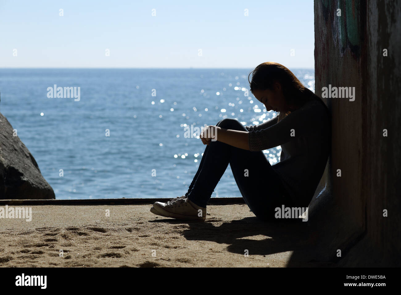 Teen Mädchen einsam und Traurigkeit am Strand mit dem Meer im Hintergrund Stockfoto