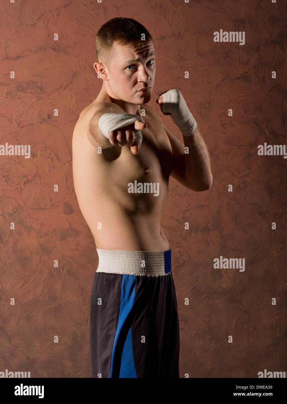 Drilliche hübscher junger Boxer mit einem energischen Gesichtsausdruck zeigte auf der Kamera mit der bandagierte hand Stockfoto