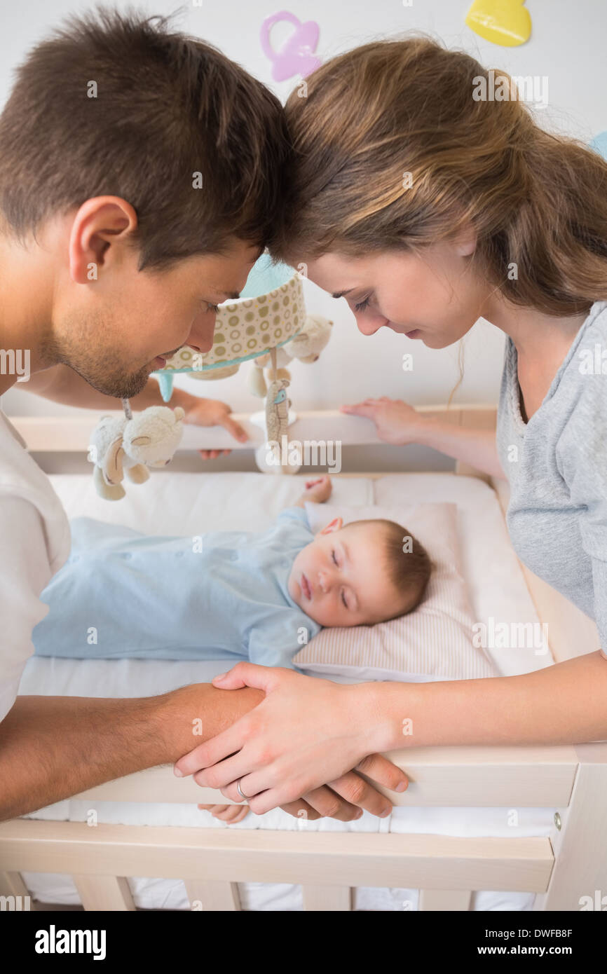 Glückliche Eltern, die gerade über Baby Sohn in Krippe Stockfoto