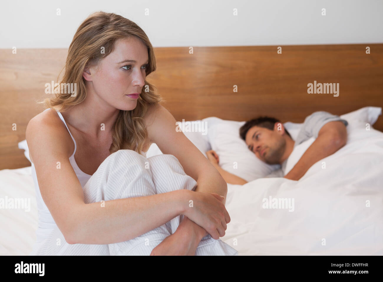 Traurige Frau mit Mann schlafen im Hintergrund Stockfoto