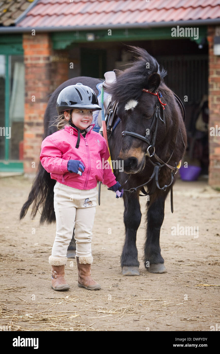 Ein vier Jahre altes Mädchen mit einem Pony während einer Reitstunde in North Lincolnshire, England, 2014 Stockfoto