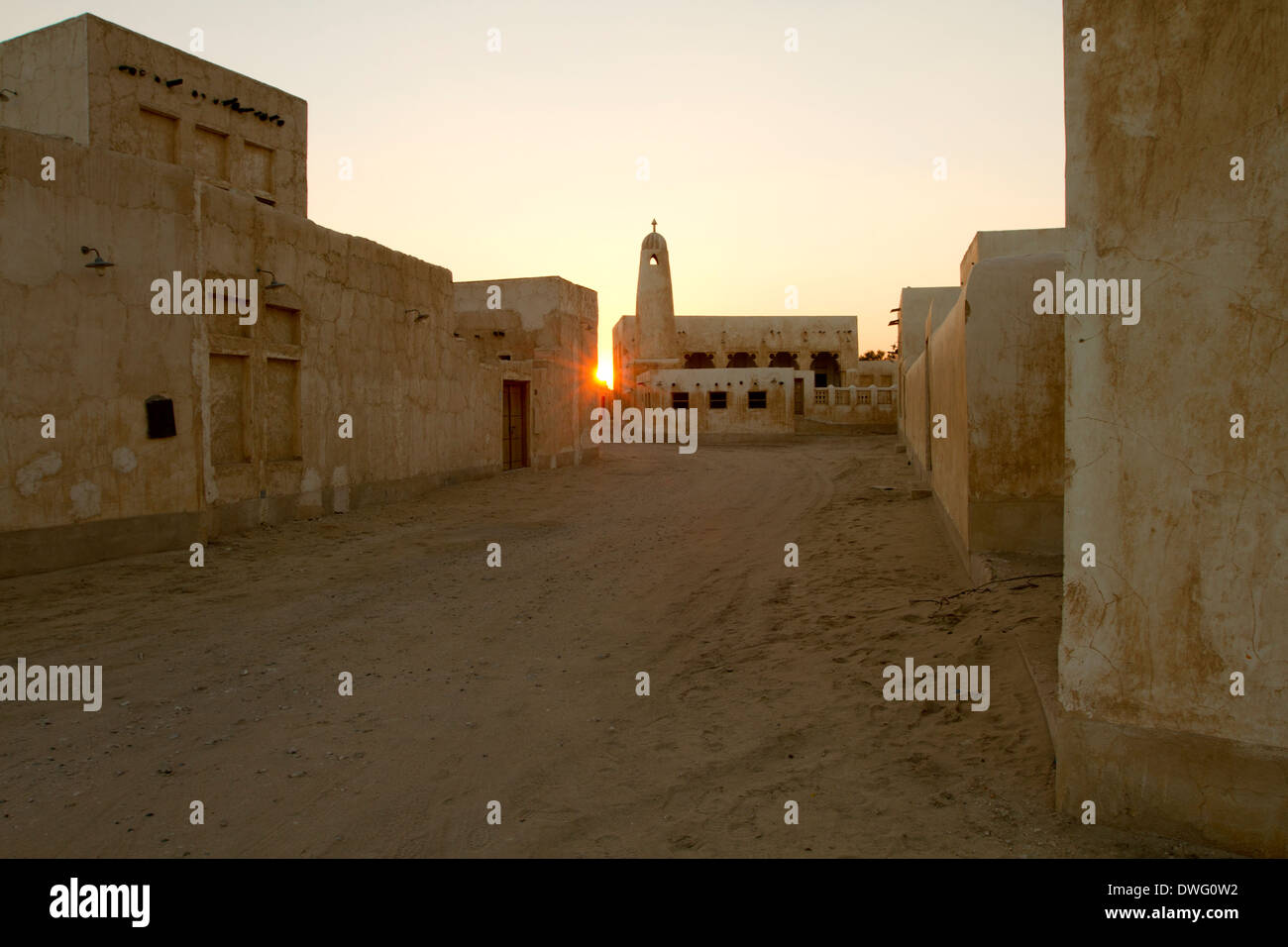 Sonnenuntergang am traditionellen Häusern und Minarett neben Strand in Al Wakra, Katar Stockfoto