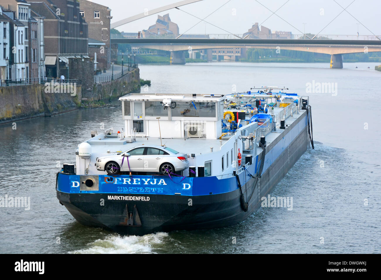 Maastricht Limburg der kommerzielle Verkehr auf der Maas fährt mit einem Motorschiff entlang der Stadtlandschaft, beladen mit einem eigenen Auto des Besatzungsmitglieds Stockfoto