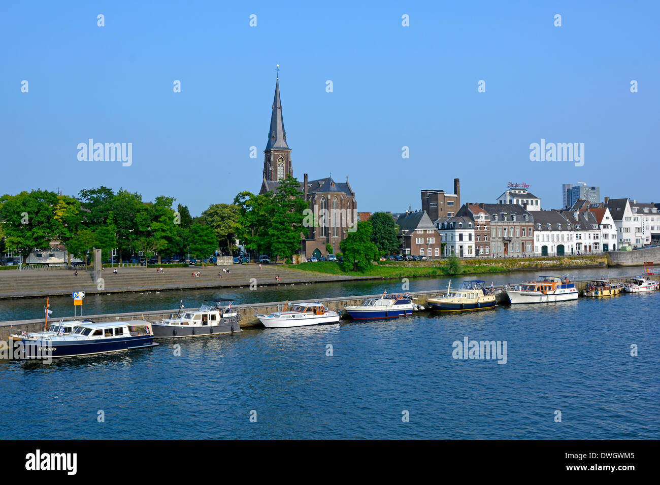 Maastricht River Maas (maas) und lange Kaimauer, die den Hauptwasserweg trennt, bieten Anlegeplätze für Motorboote Kirchturm Wahrzeichen EU Stockfoto