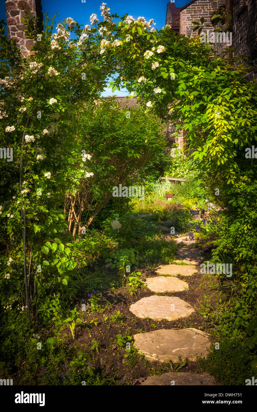 Sommergarten mit gepflasterten Weg und Rankgitter Stockfoto