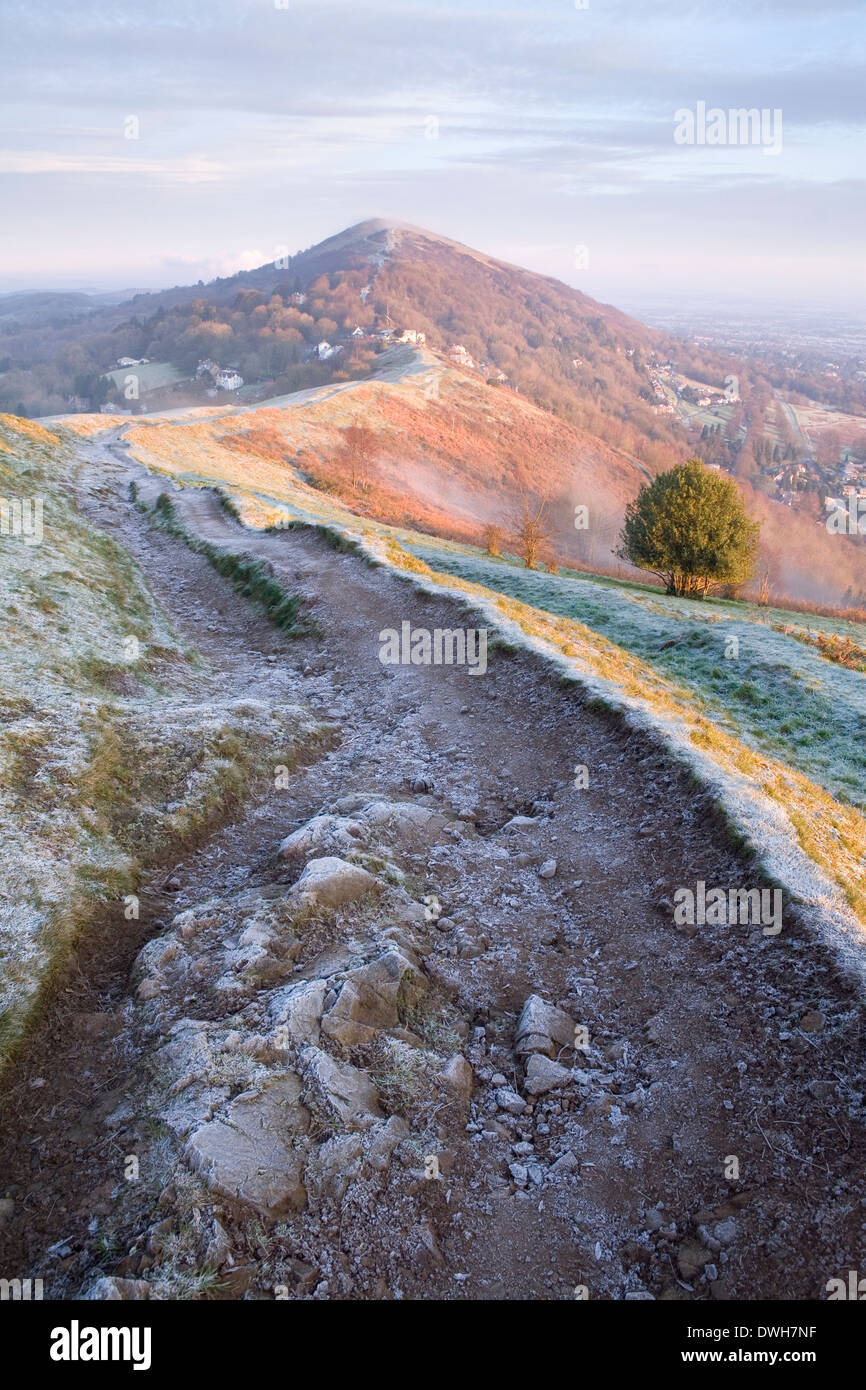 Ein stark abgenutzter Fußweg auf Ausdauer Hügel, Malvern Hills, ist im Schatten von dem starken Licht des Sonnenaufgangs gegossen. Stockfoto