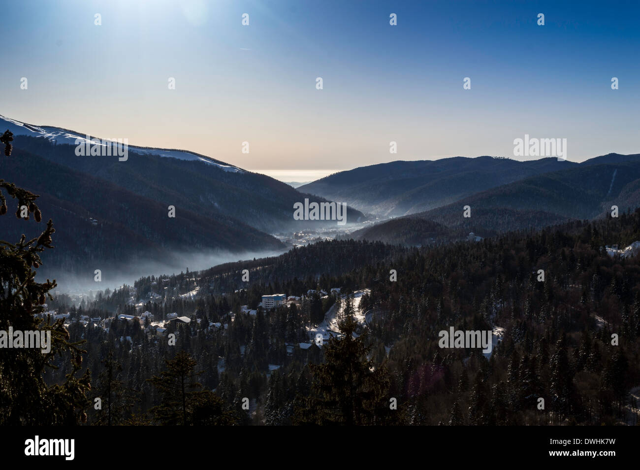 Sonnenaufgang, Stadt zwischen Bergen und bewölktem Himmel und Nebel Stockfoto