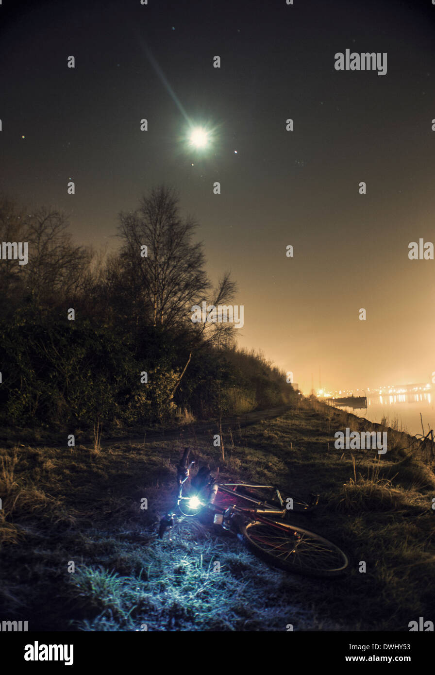 Nacht Zeit Schuss ein Fahrrad neben einem Fluss. erfassen den Mond und Sterne und andere Lichter auf dem Fluss. Stockfoto