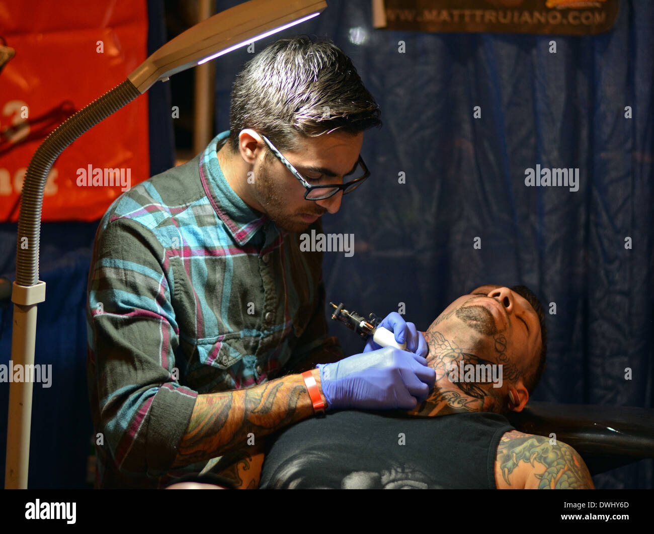 Ein Tattoo-Künstler arbeiten auf dem Nacken eines Menschen auf der New York City Tattoo Convention im Roseland Ballroom in Midtown Manhattan, NY Stockfoto